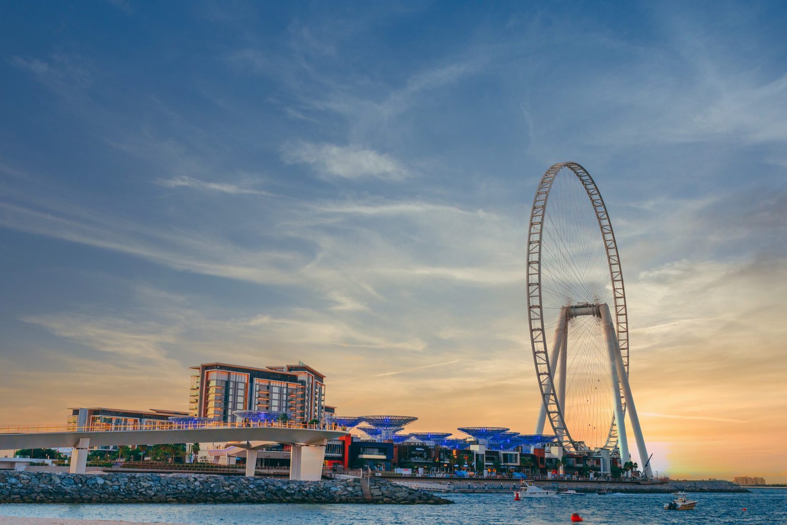 Low angle shot of modern design of a building with a huge Ferris wheel at Bluewaters island in Dubai luxury yacht dubai marina<br />